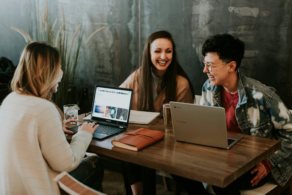 Three friends laughing over coffee at a table