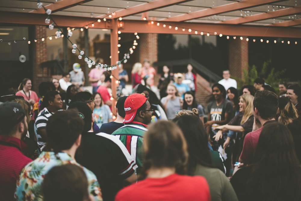 A crowd at an outdoor party under string lights