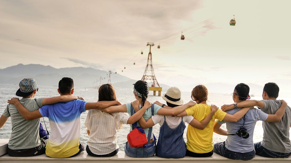 Friends sitting in a row with arms around each other